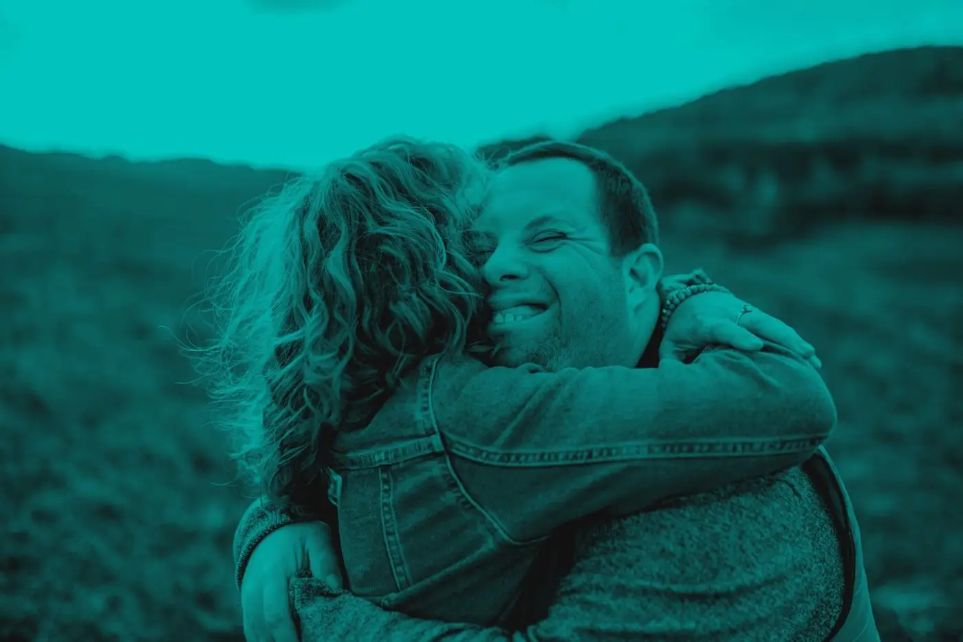 Two people embracing outdoors and smiling